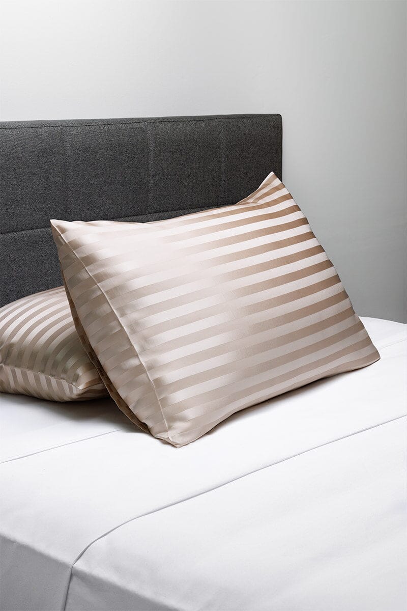 Striped silver silk pillowcase with smooth, lustrous finish on white bedding.